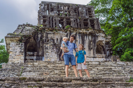 Father with his toddler and teenage sons exploring the ancient pyramids of Palenque, Mexico, surrounded by dense jungle. Cultural heritage and adventure travel conceptの写真素材