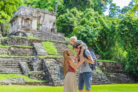 Mom, dad and baby son exploring the ancient pyramids of Palenque, Mexico, surrounded by dense jungle. Cultural heritage and adventure travel conceptの写真素材