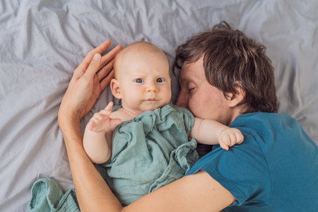A father lovingly embraces his 3-month-old baby, wrapped in a soft muslin swaddle. A heartwarming display of tenderness and connection. Parenthood, love, and nurturing bond conceptの写真素材