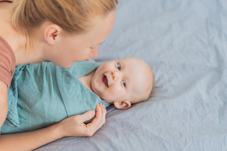 A mother gently wraps her baby in a soft muslin swaddle, providing warmth and comfort. A tender...