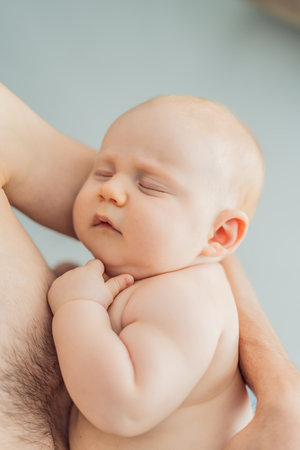 A baby peacefully falls asleep in his fathers arms, skin-to-skin. A heartwarming and intimate moment of love, bonding, and parenthood, showcasing the deep connection between father and childの写真素材