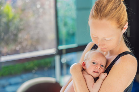A mother lovingly embraces her newborn baby, holding them close to her chest. A tender moment of warmth, security, and deep maternal love, symbolizing bonding, comfort, and the unbreakable connection between mother and childの写真素材