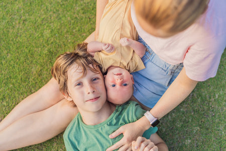 Young mother, teenage son, and one-month-old baby enjoying quality family time in the park. Multigenerational bonding and outdoor family love conceptの写真素材