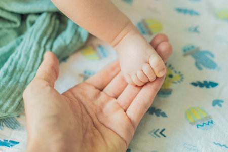 Fathers hand gently holding his babys tiny foot, symbolizing love, protection, and family bond....
