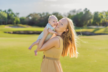 Mother and newborn baby on a meadow in the park. Tender bonding moment in nature. Parenthood, love, and family connection conceptの写真素材