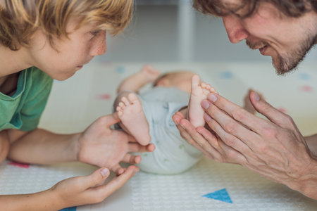 Father, son, and newborn baby lying on the floor in a cozy nursery, celebrating the arrival of their newest family member. Parenthood, bonding, and family love conceptの写真素材