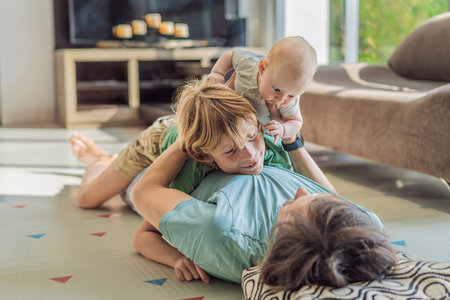Father, son, and newborn baby lying on the floor in a cozy nursery, celebrating the arrival of their newest family member. Parenthood, bonding, and family love conceptの写真素材