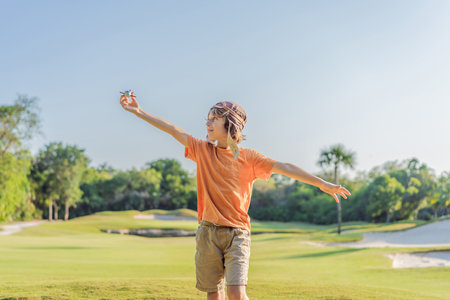 Boy wearing a pilot hat running through the grass with a toy airplane, dreaming of adventures. Childhood, imagination, and freedom conceptの写真素材