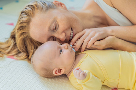 Mother and baby lying on a play mat. Tender bonding moment, cozy childhood atmosphere, and early development. Parenting, love, and infant care conceptの写真素材