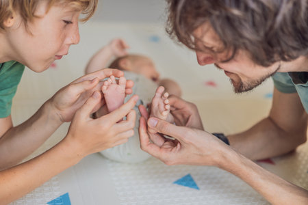 Father, son, and newborn baby lying on the floor in a cozy nursery, celebrating the arrival of their newest family member. Parenthood, bonding, and family love conceptの写真素材