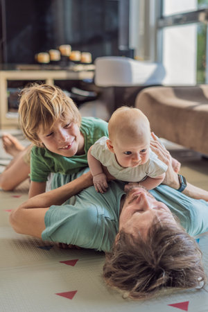 Father, son, and newborn baby lying on the floor in a cozy nursery, celebrating the arrival of their newest family member. Parenthood, bonding, and family love conceptの写真素材