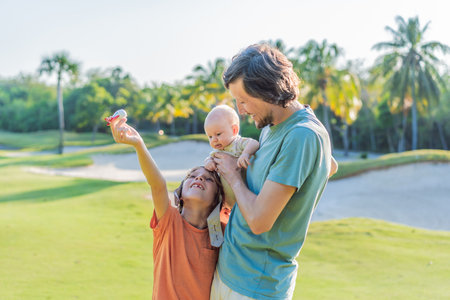 Father with his two sons in the park, the older boy wearing a pilot hat and holding a toy airplane...