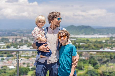 Father with his two sons standing in front of Popocatepetl volcano in Mexico, surrounded by clouds, enjoying a scenic family adventure and breathtaking outdoor viewの写真素材