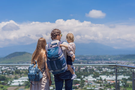 Mom, dad, and their little son standing together in front of Popocatepetl volcano in Mexico surrounded by clouds, enjoying a peaceful and breathtaking family travel momentの写真素材