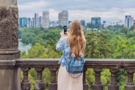 Young woman tourist standing near Chapultepec Castle in Mexico City, exploring the historic landmark. Solo travel, cultural heritage, tourism, and adventure conceptの写真素材