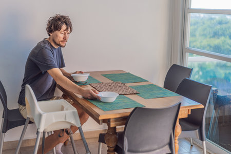 A man preparing breakfast at a kitchen table in a bright modern home, captured in a candid moment...