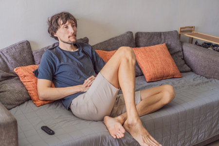 A man watching a football match on television at home, fully focused and relaxed in a cozy living room. Leisure time, sports entertainment, weekend relaxation and modern digital lifestyle conceptの写真素材