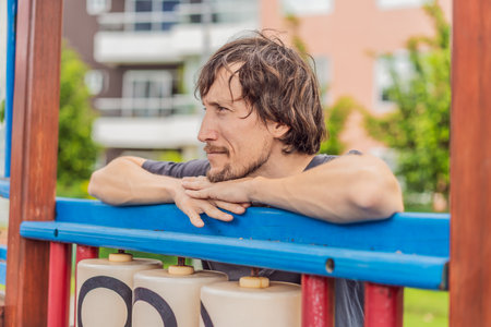 A man playing with his small son on a playground, laughing and engaging in active fun together in a...
