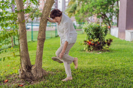 Elderly woman walking in the park, enjoying fresh air, sunlight, and peaceful nature. Concept of active aging, wellness, healthy lifestyle, positive aging, mobility, and outdoor relaxationの写真素材