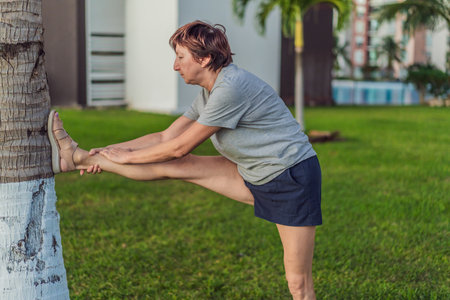Elderly woman exercising on a grassy lawn, staying active, strong, and healthy outdoors. Concept of...