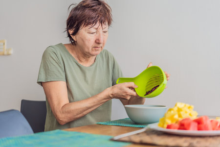 Unaltered senior woman enjoying a calm breakfast at the dining table in a bright home setting....
