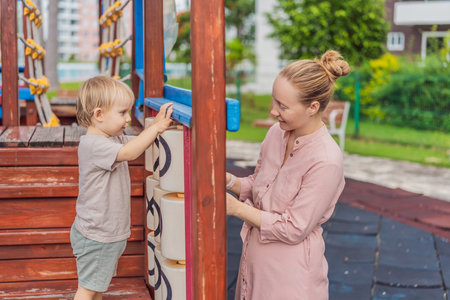 A mother playing with her young son at an outdoor playground, enjoying joyful family time and positive parenting moments. Childhood fun, bonding, laughter and carefree early years conceptの写真素材