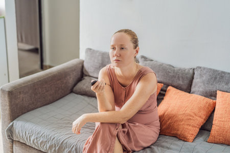 Woman relaxing at home and watching a movie on the television, enjoying a peaceful evening atmosphere. Cozy lifestyle, leisure and entertainment concept, representing comfort, calmness and modern home livingの写真素材