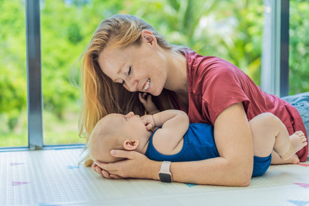 Mother and baby lying on a soft play mat at home, playing, talking and sharing a joyful moment...