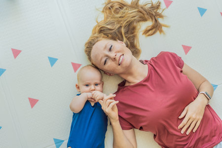 Mother and baby lying on a soft play mat at home, playing, talking and sharing a joyful moment...