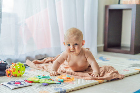 Little baby playing with toys on a soft baby play mat at home. Early childhood development, sensory...