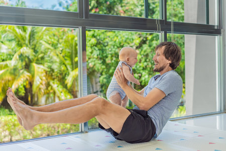 Father exercising with his small baby at home, active parenting and healthy lifestyle. Strong family...