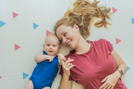 Mother and baby lying on a soft play mat at home, playing, talking and sharing a joyful moment...