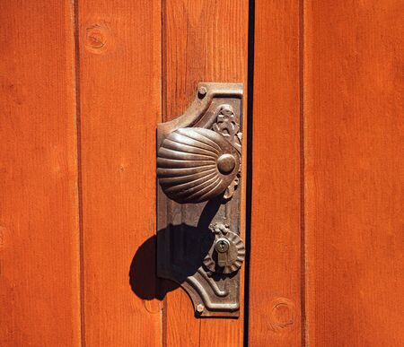 Antique doorknob on a wooden door, closeup. Antique metal door handle. Old wooden entrance door with antique door handle.の写真素材