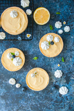 Lemon curd and blueberry jam tarts with meringue and basil leaves Chamomiles whole and slices of...