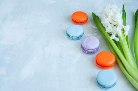 White hyacinth flower and colorful macarons cookies on a stone background. Close up and copy space.の写真素材