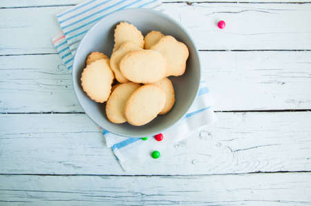 A group of butter shortbread cookies in a bowl on white wooden background. Selective focus. Close up.の写真素材