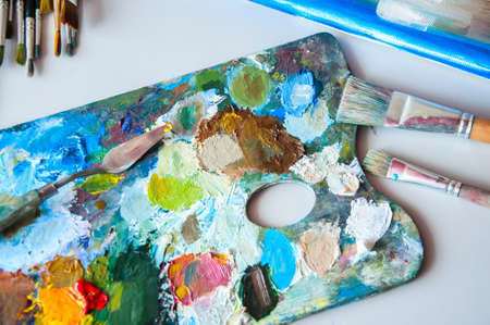 Art brushes and palette with oil paints on a table. Painting concept.の写真素材