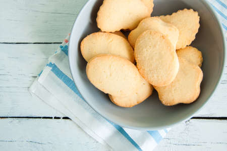 A group of butter shortbread cookies in a bowl on white wooden background. Selective focus. Close up.の写真素材