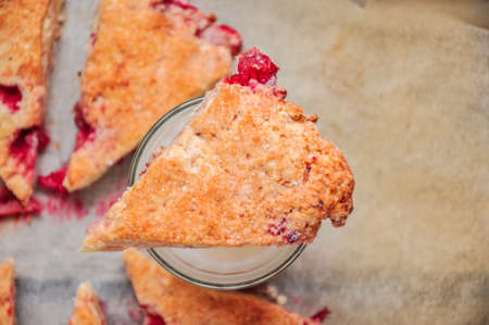 Freshly baked strawberry scone segments with pieces of berries on aglass of milk. Close up and Top view.の写真素材