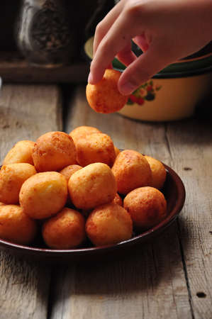 Small balls of freshly baked homemade cottage cheese doughnuts in a plate on a wooden background....