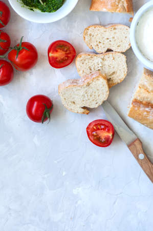 Set of ingredients for bruschettas with goat cheese, pesto sauce and tomatoes and baguette on a...