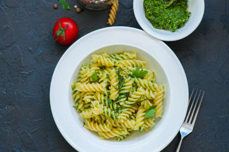 Top view of pasta pesto sauce served in a white plate on a black slate background. Copy space.の写真素材