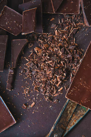 Whole and pieces of dark chocolate bars on a darkbackground  at monochrome setting. Top view.Toned.の写真素材