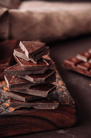 Pieces of dark chocolate on a wooden board at monochrome setting. Toned.の写真素材