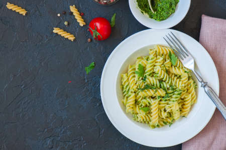 Top view of pasta pesto sauce served in a white plate on a black slate background. Copy space.の写真素材