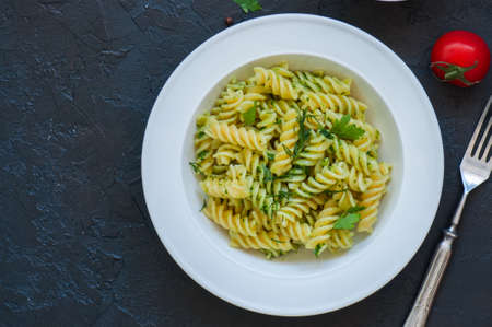 Top view of pasta pesto sauce served in a white plate on a black slate background. Copy space.の写真素材