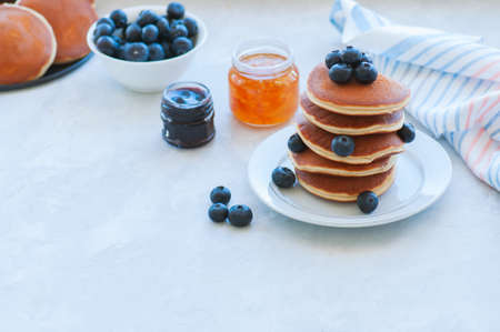 Stack of fluffy panckes with fresh berries, blueberry and orange jam served on a white plate. Healthy breakfast concept.の写真素材