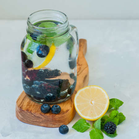 Infused detox water with lemon blackberry blueberry and mint leaves in a mason jar