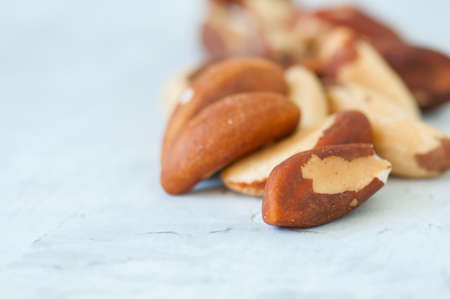 Close up of brasil nuts in a wooden plate on white background. Copy space.の写真素材