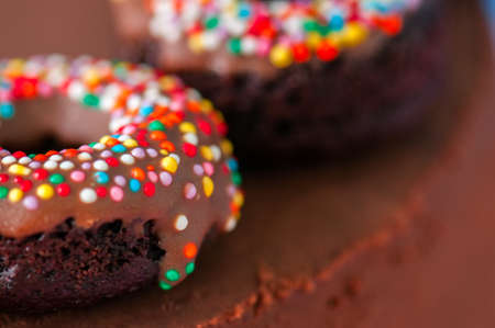 Close up of chocolate baked doughnuts with chocolate glaze with confetti on a cake. の写真素材